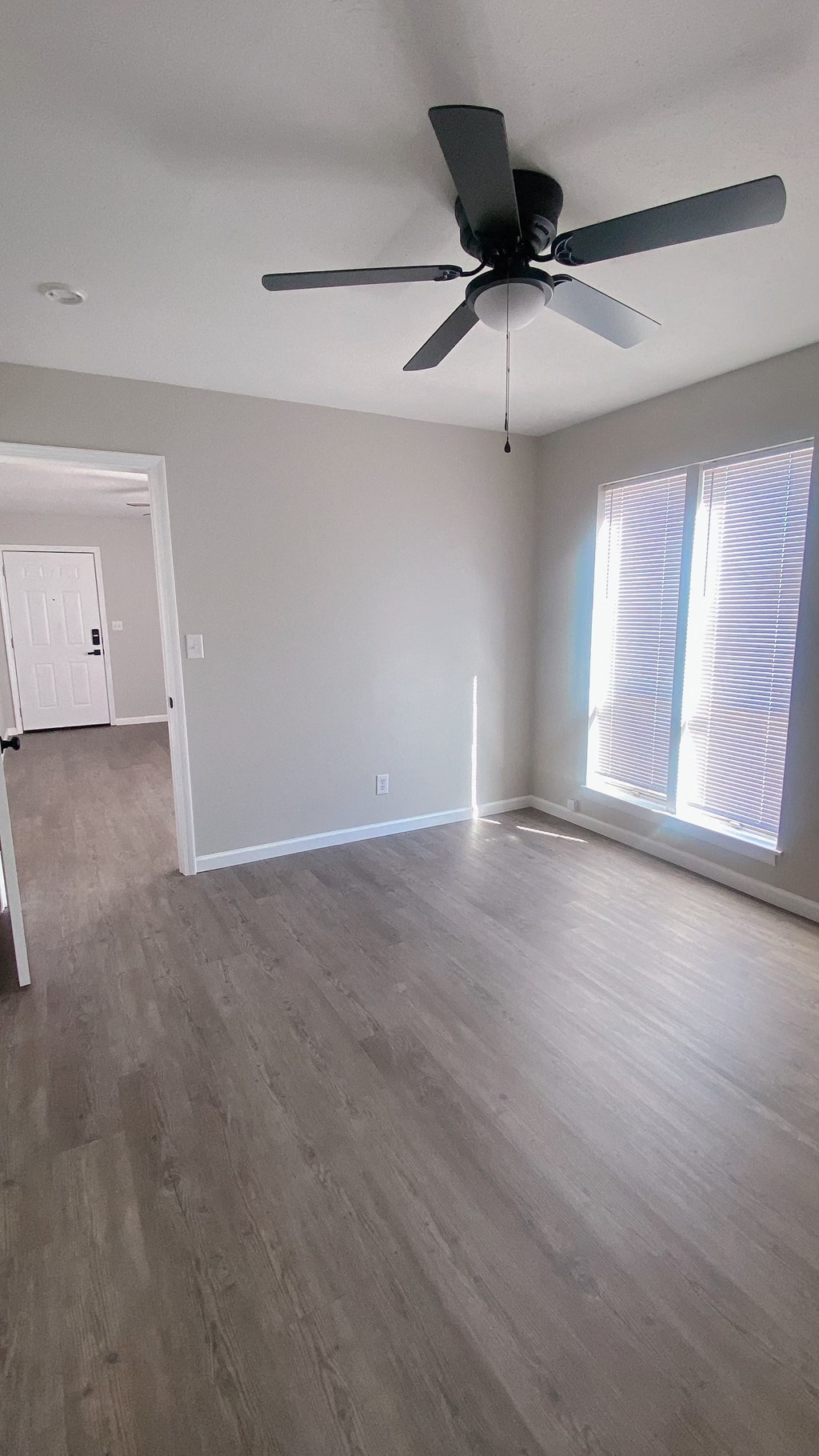 an empty living room with wooden floors and a ceiling fan