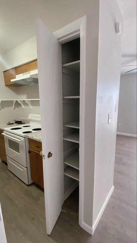 a kitchen with an open pantry and a stove and