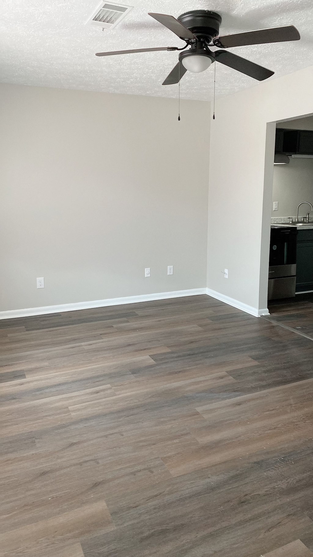 an empty living room with wooden floors and a ceiling fan
