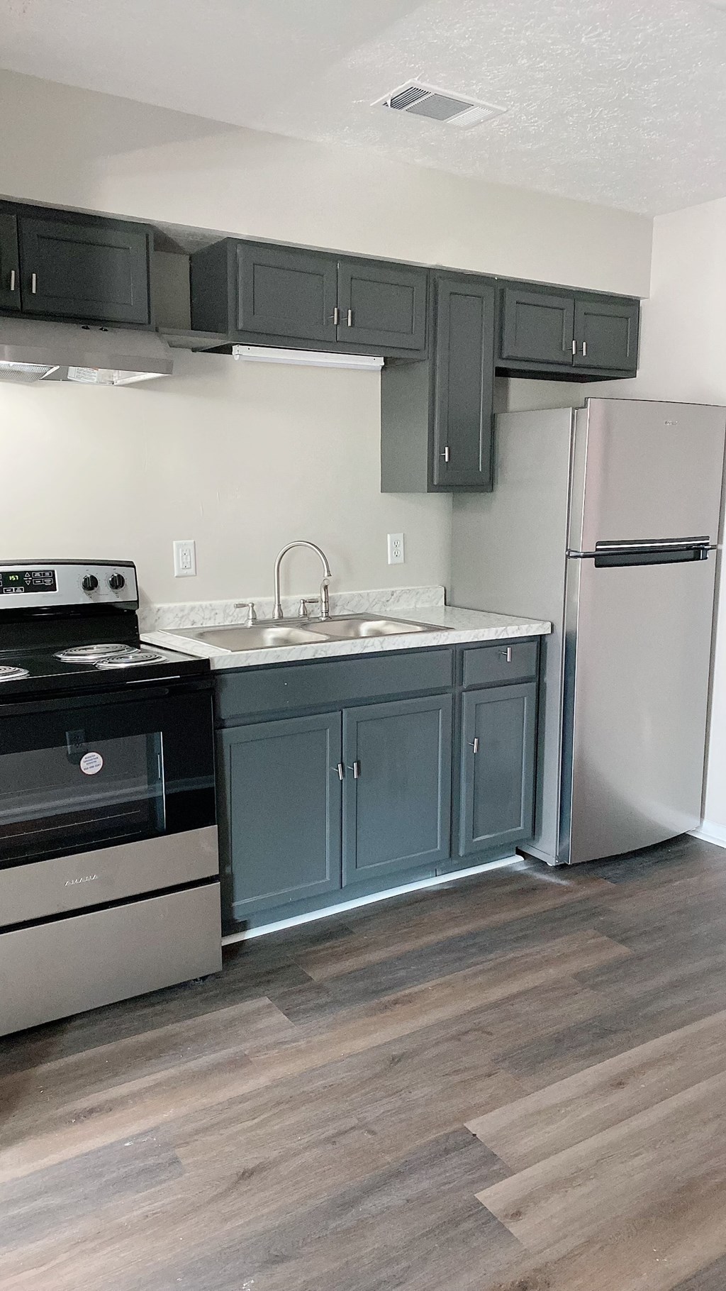 an empty kitchen with black cabinets and stainless steel appliances