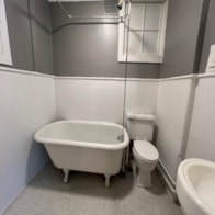 A white toilet sits next to a white bathtub in a bathroom.