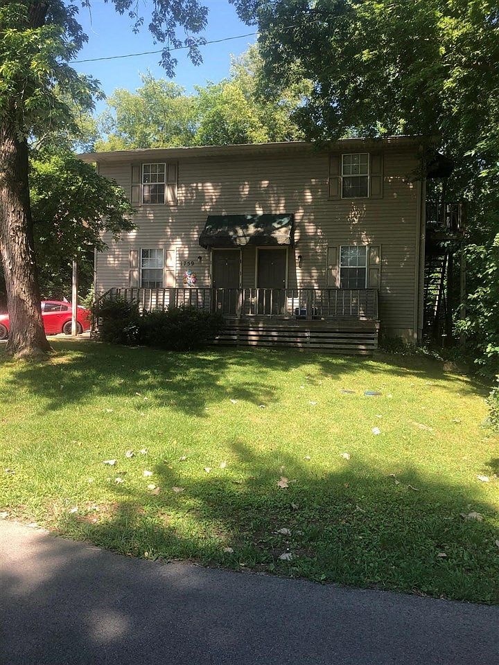 the front of a house with a yard and a tree