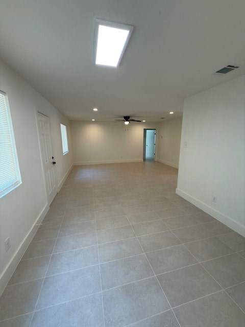 A spacious room with a skylight and a ceiling fan.