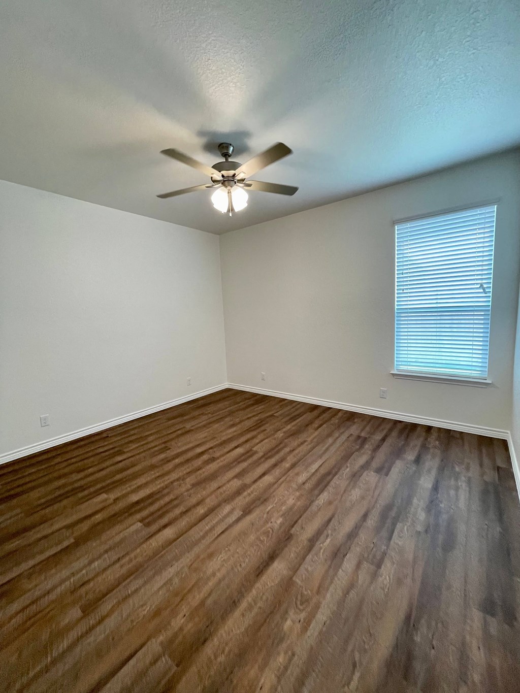 an empty living room with wood floors and a ceiling fan