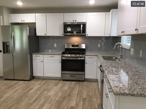 A kitchen with white cabinets and a granite countertop.