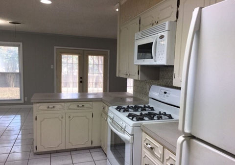 a white kitchen with a stove and a microwave