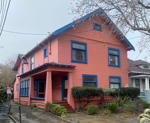 a pink house with a blue roof on a street