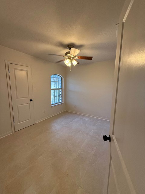 an empty living room with a ceiling fan and a window