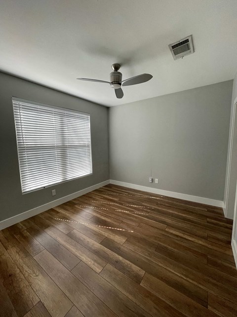 a living room with wood floors and a ceiling fan