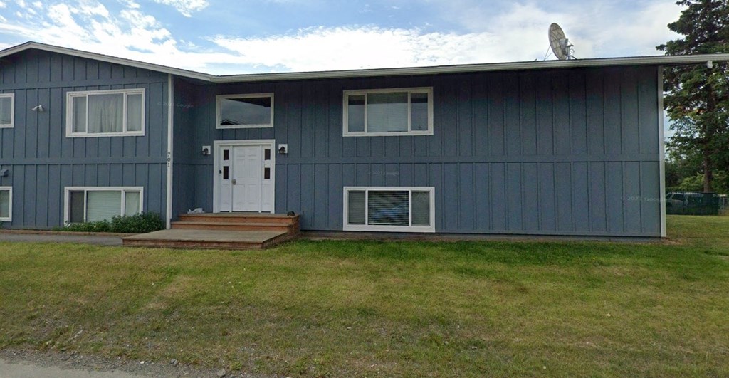 a blue house with a white door and a lawn