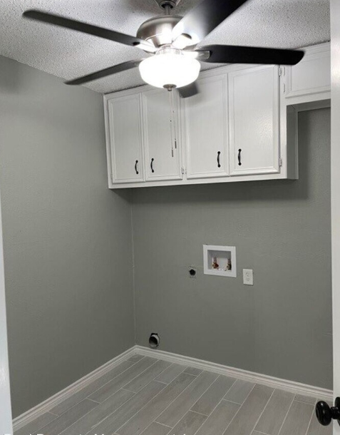 a room with a ceiling fan and white cabinets