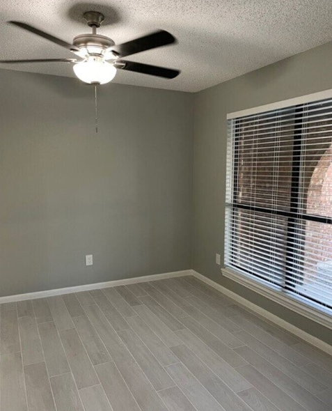 a living room with a large window and a ceiling fan
