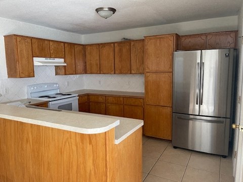 a kitchen with wooden cabinets and a stainless steel refrigerator