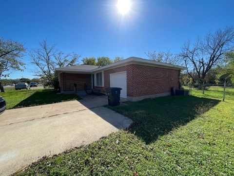a small brick house with a sidewalk in front of it