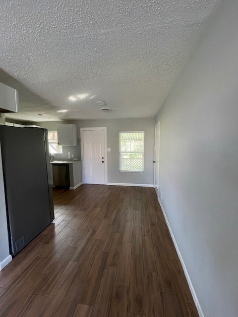 an empty living room and kitchen with a refrigerator
