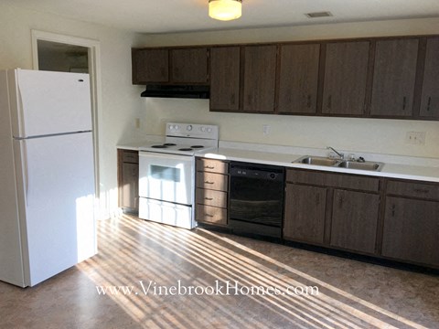 A kitchen with a white fridge and brown cabinets.