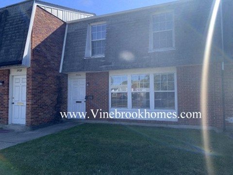 a view of the front of a brick house with a lawn