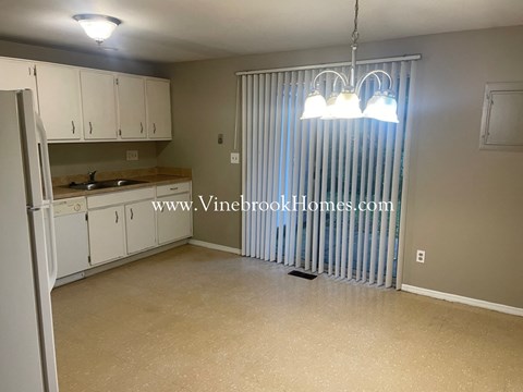 a small kitchen with a large window and white cabinets