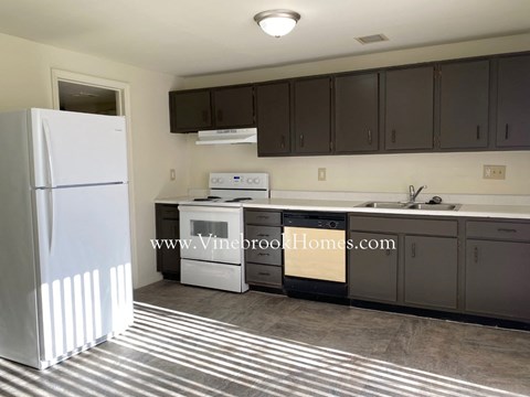 A kitchen with a white refrigerator and dark brown cabinets.
