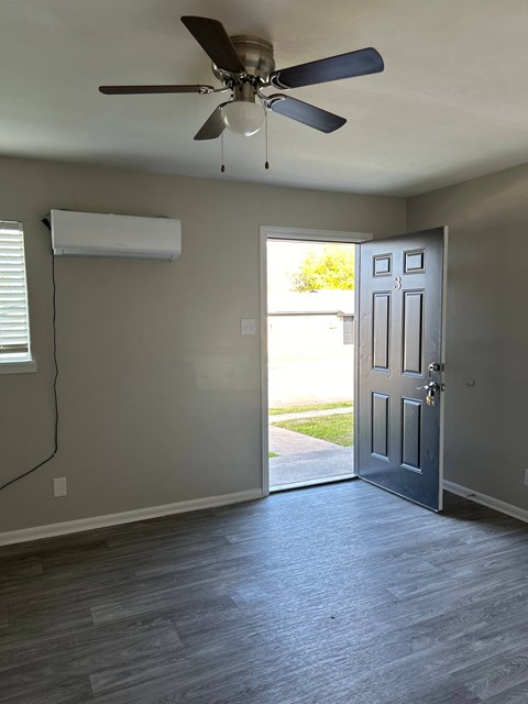 A room with a ceiling fan and a door leading outside.
