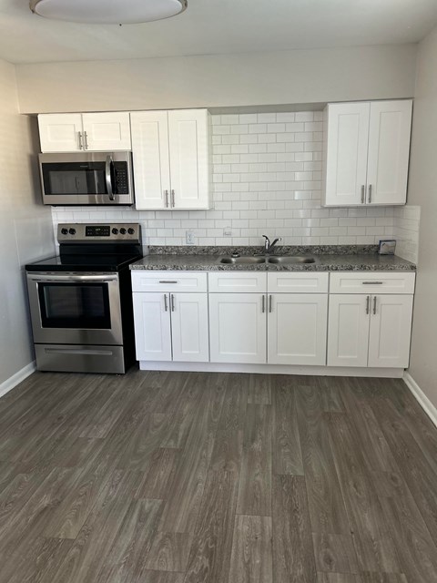 A kitchen with white cabinets and a black stove top oven.