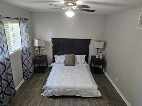 A bedroom with a bed, nightstands, and a ceiling fan.
