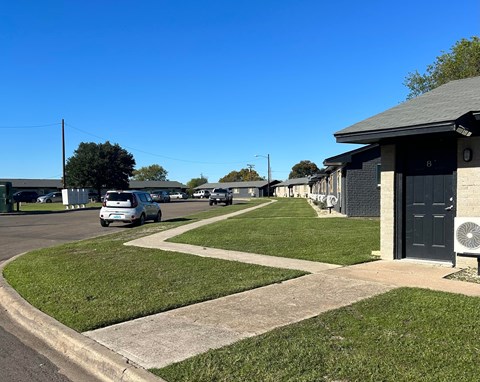 A car is parked on the side of a road in front of a building.