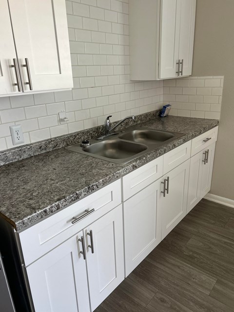 A kitchen with white cabinets and a granite countertop.