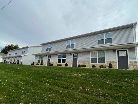 A row of houses with grey siding and dark grey doors.