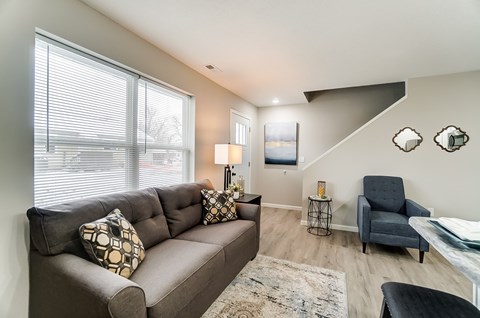 A living room with a grey couch, a black chair, and a rug.