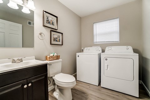 A bathroom with a white toilet, sink, and washer and dryer.