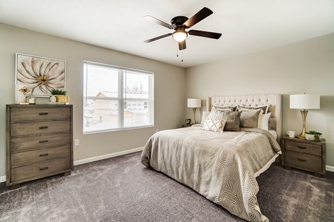 A bedroom with a large bed, a dresser, and a ceiling fan.