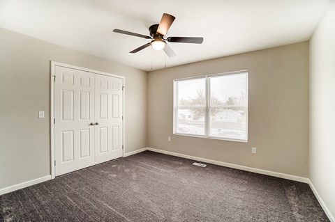 A room with a ceiling fan and a door.