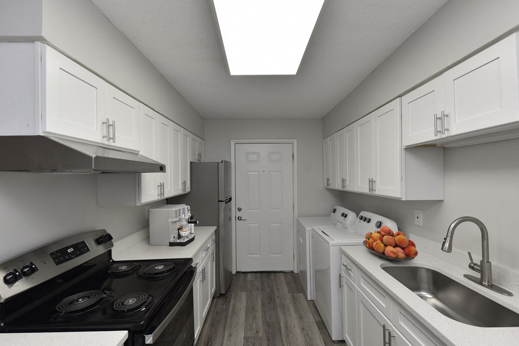 a kitchen with white cabinets and appliances and a sink