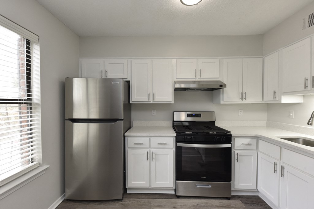 an empty kitchen with white cabinets and a stainless steel refrigerator