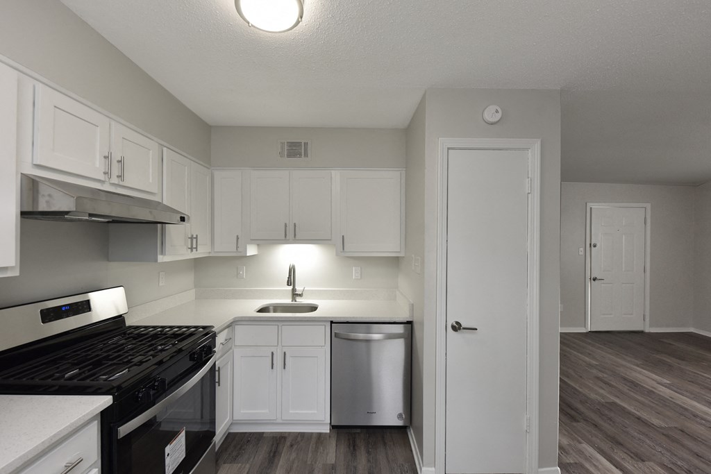an empty kitchen with white cabinets and stainless steel appliances
