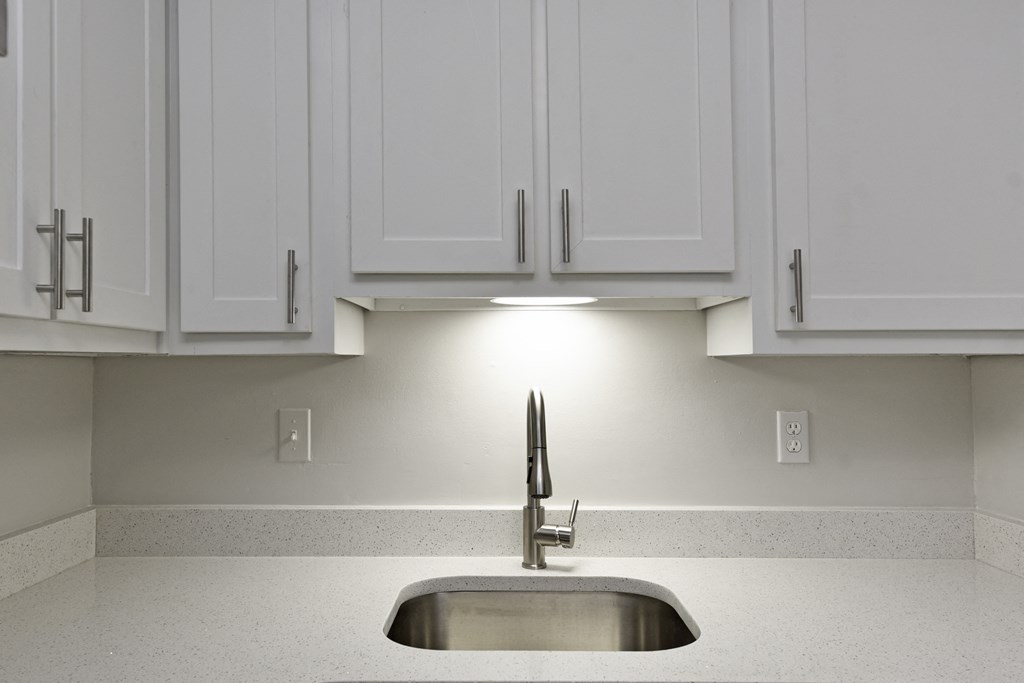 an empty kitchen with white cabinets and a sink