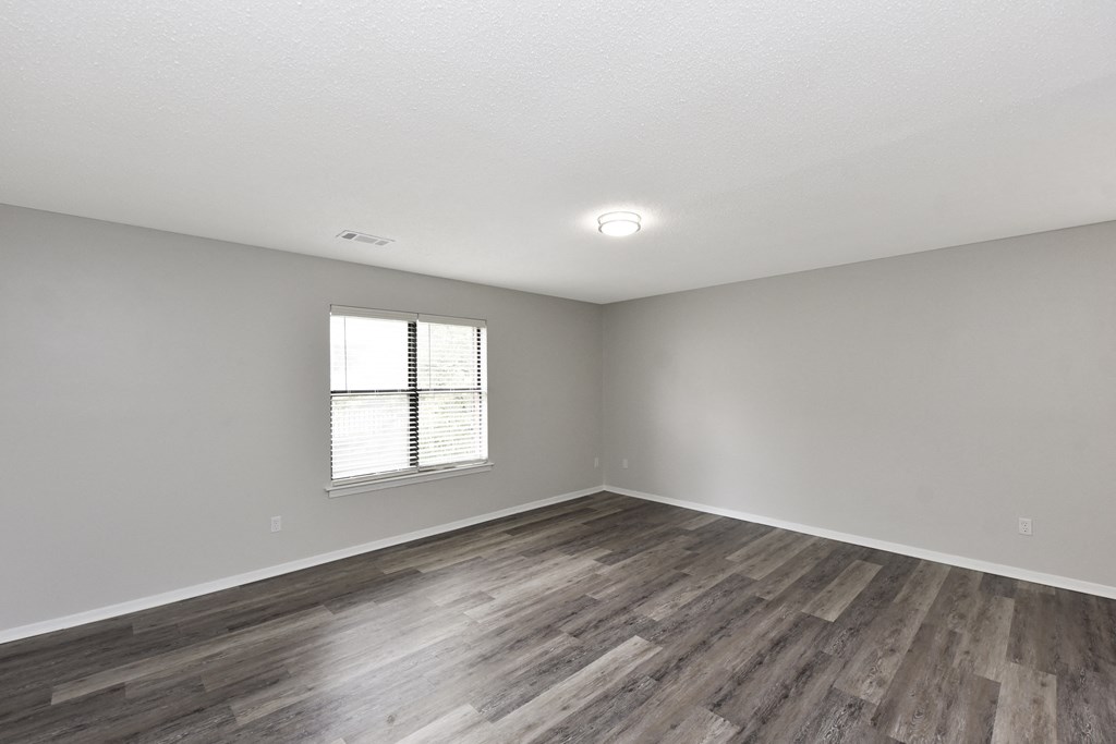 an empty living room with wood flooring and a window