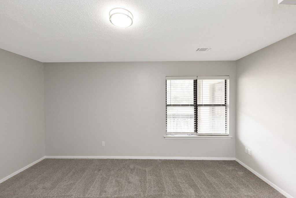 an empty room with a window and white walls
