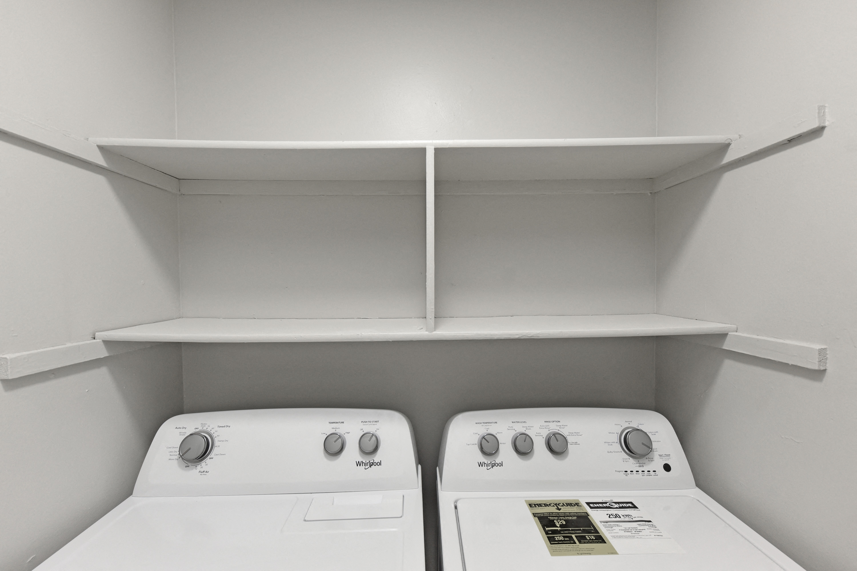 an empty laundry room with two washers and a dryer