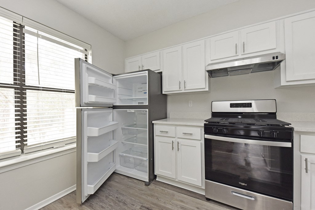 an empty kitchen with white cabinets and a stove and refrigerator