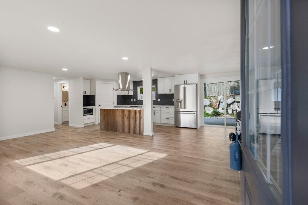 a kitchen and living room with white walls and wood floors