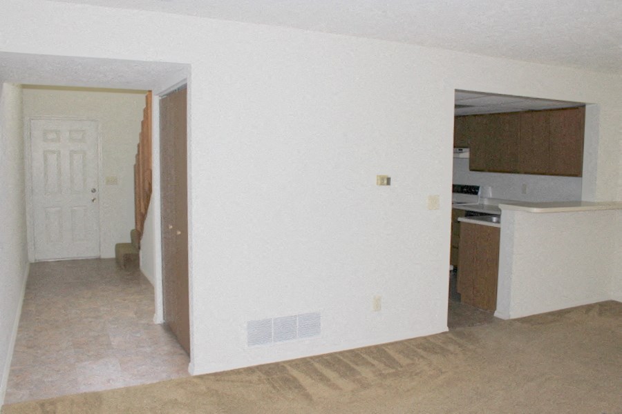 an empty kitchen with a door to the living room