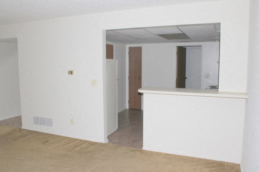 an empty living room with a counter and a mirror