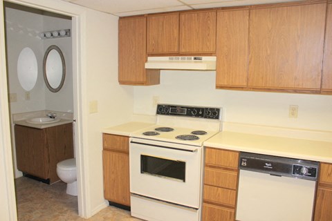 an empty kitchen with white appliances and wooden cabinets