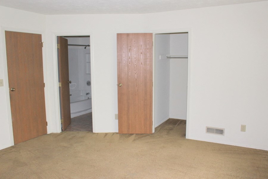 an empty room with a door to a bathroom and a closet