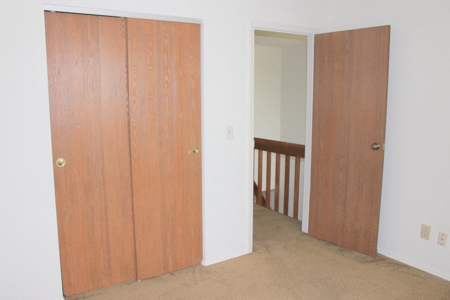 an empty room with a door to a closet and a staircase