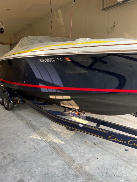 A boat with a black hull and red and yellow stripes is being towed by a trailer.