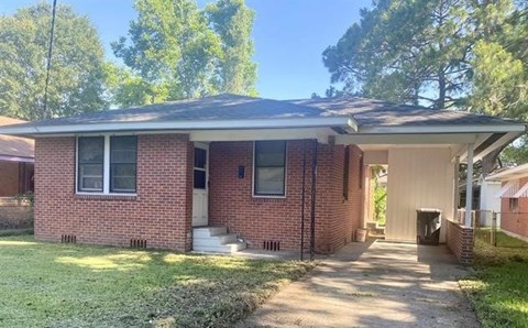 A red brick house with a white door and windows.