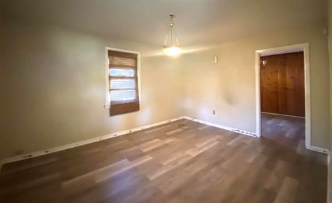 A room with wooden flooring and a window with blinds.